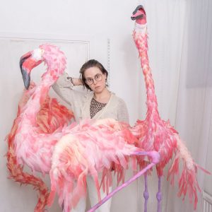 Porträtt av Maja Fredin omgiven av rosa, textila flamingor